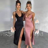 Two women in black and pink dresses standing in a decorated room with candles.